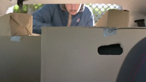 Man arranges parcels in the trunk of the car Stock Footage 130284124