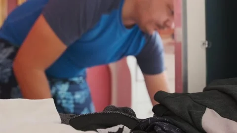 Man arranging clean dry clothes into sliding wardrobe, organizing folded Stock Footage 333770359