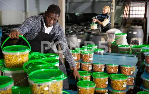 Man arranging plastic buckets with pickled olives Stock Photos