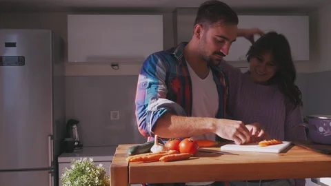 Man arranging salad in the kitchen while girlfriend is smiling Stock Footage 97643373