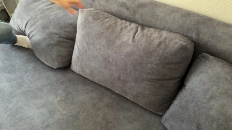 Man arranging sofa cushions at home, interior adjustment, home comfort, daily Stock Footage 337109234