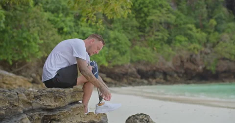 Man with artificial bionic leg lacing his running sneakers preparing for workout Stock Footage 195001687