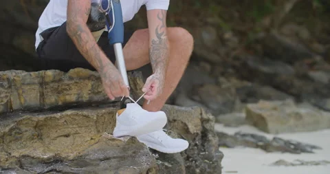 Man with artificial bionic leg lacing his running sneakers preparing for workout Video stock 201366156