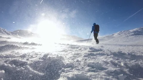 Man ascending on splitboard with climbing skins defying severe blizzard Stock Footage 102110529