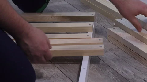 A man assembles the base for mattresses. Attaching slats. Ottoman assembly... Stock Footage 303857103