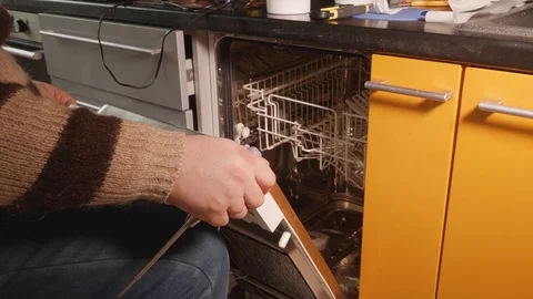 Man assembles dishwasher after repairing it. Handy man's hands close up view. Stock Footage 107973335