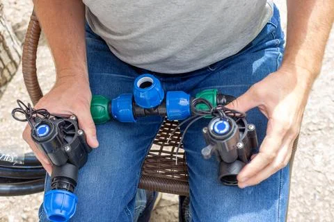 A man assembles a drip irrigation system by assembling pipeline components .. Stock Photos