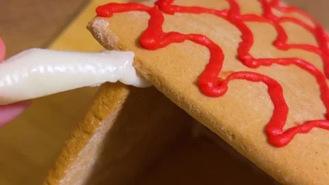 Man assembles gingerbread house on table, glues roof with icing Stock Footage 317587609