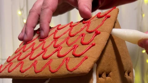 Man assembles gingerbread house on wooden stand on table Stock-Footage 318975350