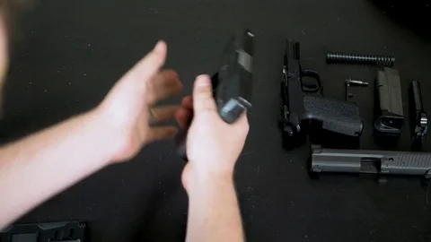 Man assembles a handgun on a black table Stock Footage 76166124