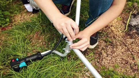 A man assembles the handle of string trimmer in the garden. Stock Photos