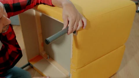 A man assembles a lounge chair on his own. The man screws the support leg to the Stock Footage 165841956
