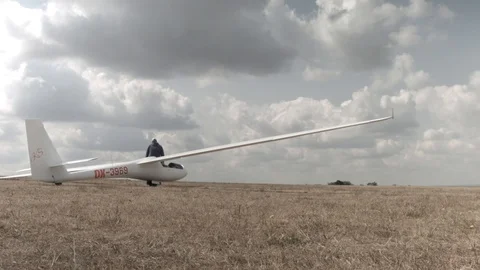 Man assembles a perspex gliders cockpit on a grass airstrip at a small Video stock 101625231