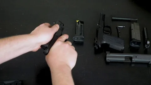 Man assembles two handguns on a black table Stock Footage 76166207