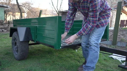 A man assembles a walk-behind tractor trailer. Stock Footage 316827106