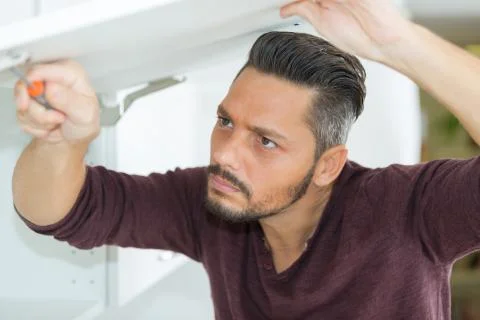 Man assembles wardrobe at home Stock Photos