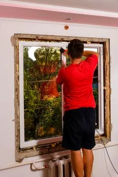 The man assembles the window, installs the double-glazed windows and fastens  스톡 사진