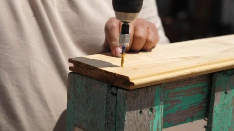 Man assembles wooden structure with power drill and long screws Stock Footage 308018718