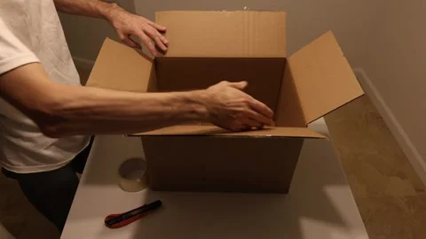 Man assembling and sealing cardboard box using tape and utility knife Stock Footage 327067300