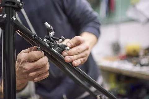 Man assembling the brake system of a bicycle as part of the maintenance servi Stock Photos