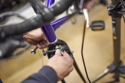 Man assembling the brake system of a bicycle as part of the maintenance servi Stock Photos