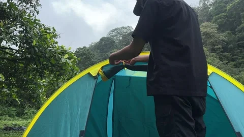 Man Assembling Camping Tent in Lush Forest Mountains, Medium Shot Stock Footage 323585785