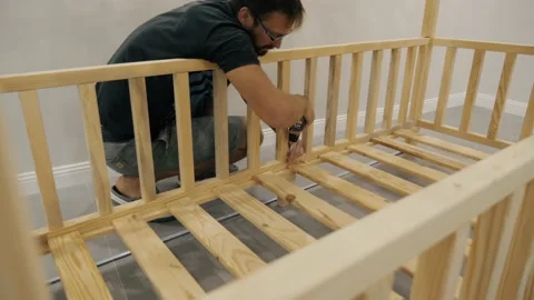 Man assembling childish wooden bed drilling plank use screwdriver comfortable Stock Footage 233469715