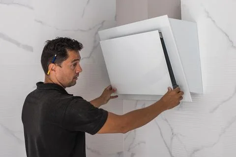 Man assembling an extractor fan in a kitchen Stock Photos