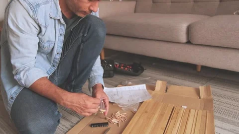 Man assembling flat pack furniture at home for renovation Stock Footage 329705944