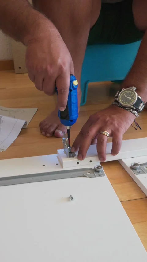 Man assembling flat-pack furniture with electric screwdriver Stock Footage 341443282