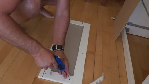 Man assembling flat pack furniture using a power screwdriver Stock Footage 341443574