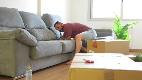 Man assembling a new gray sofa in a living room Stock Footage 340914179