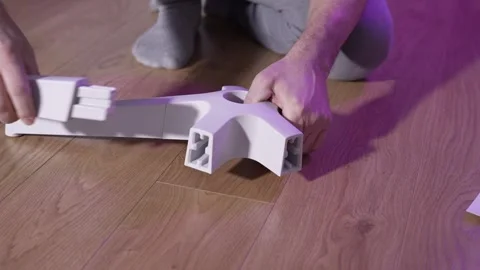 Man assembling office chair base by inserting legs into plastic hub on wooden Stock Footage 327910000