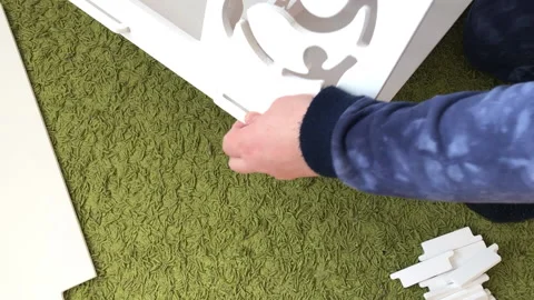 A man is assembling a plywood computer desk. Connects the elements of a com.. Stock Footage 236690033