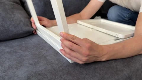 Man assembling small table or stool frame at home, furniture setup process, home Stock Footage 337109235