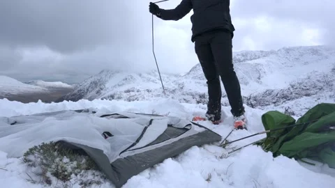 A man assembling tent poles while camping in alpine mountain landscape 動画素材 147033661
