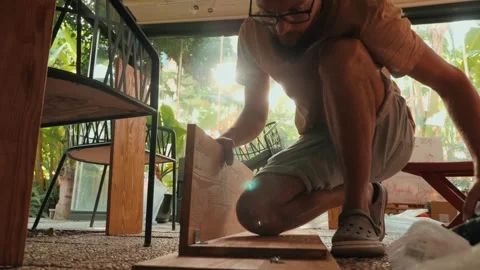 Man assembling wooden shelf use screwdriver screws carpenter tools outdoor Stock Footage 247769943