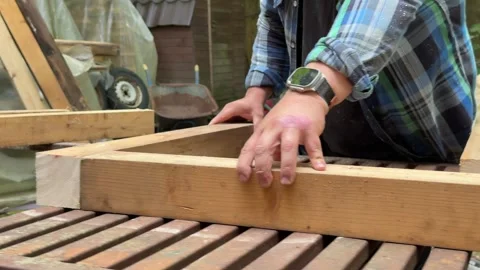 Man Assembling Wooden Structure During Outdoor DIY Project Video stock 342630556