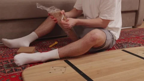 Man assembling wooden table following instruction manual Vidéo 346159405