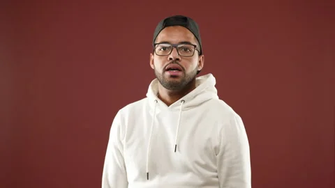 Man Assertively Gesturing Stop with Hand in a White Hoodie and Cap Video stock 270253376