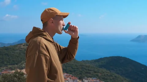 Man with asthma attack using inhaler outdoors Stock Footage 330480748