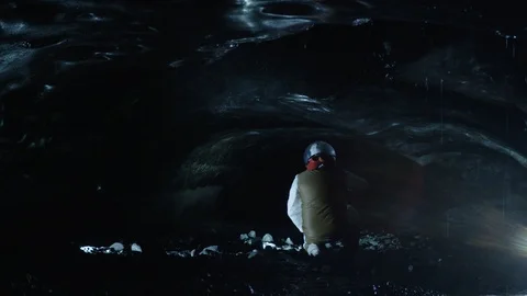 Man in astronaut suit crouch in an ice cave, Iceland Video stock 104238595