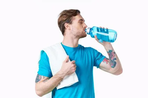 Man athlete drinks water from a bottle on a white background and a towel on his Stock Photos