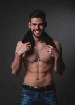 A man of athletic build in the background, smiling, holding a t-shirt Stock Photos