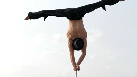 A man of athletic build performs complex gymnastic exercises in a field at Stock Footage 145404498