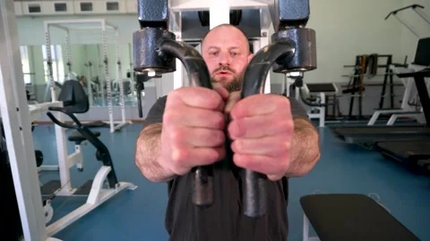 A man with an athletic build is working out on a machine in a gym. He is de.. Video stock 291292224