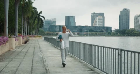 Man with athletic figure goes for workout in morning with yoga mat and towel Stock Footage 277138047