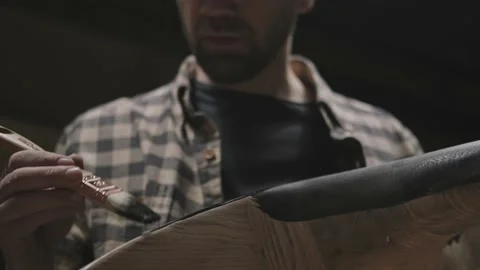 A man in an atmospheric carpentry workshop paints furniture Stock Footage 144361472