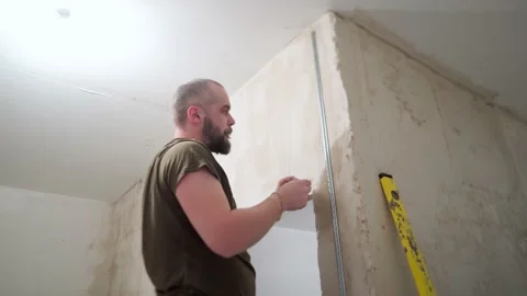 A man attaches a construction profile to the wall Stock Footage 169624682