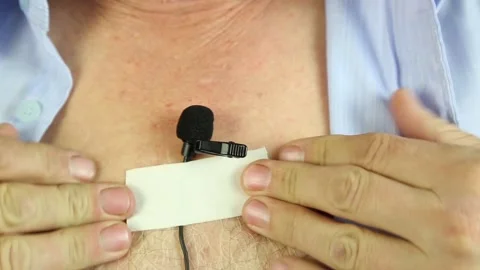 A man attaches a hidden microphone to his chest with an adhesive tape. Stock-Footage 87871763